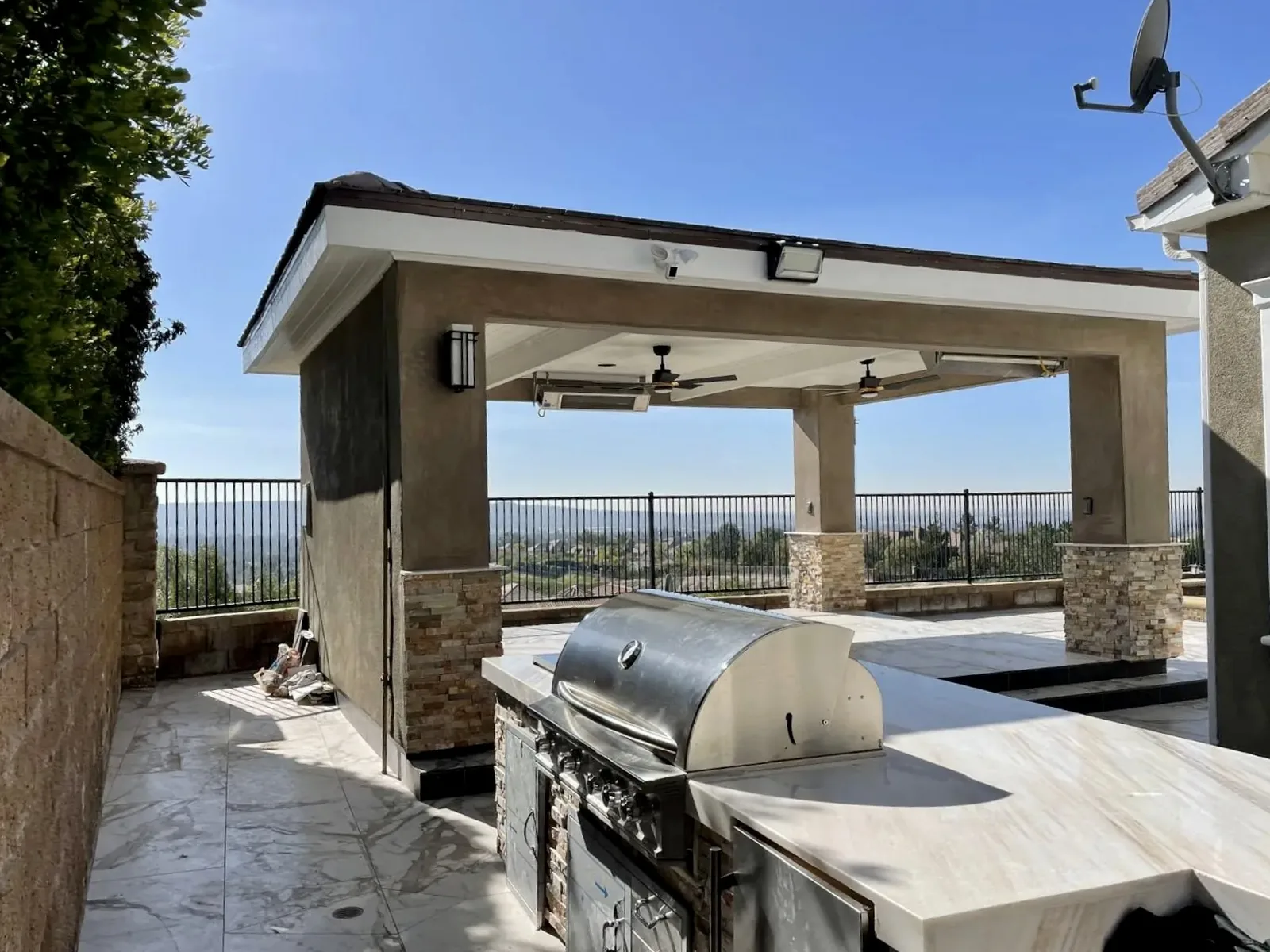 Outdoor kitchen with grill and stone columns under a covered patio built by Mau & Co in Los Angeles