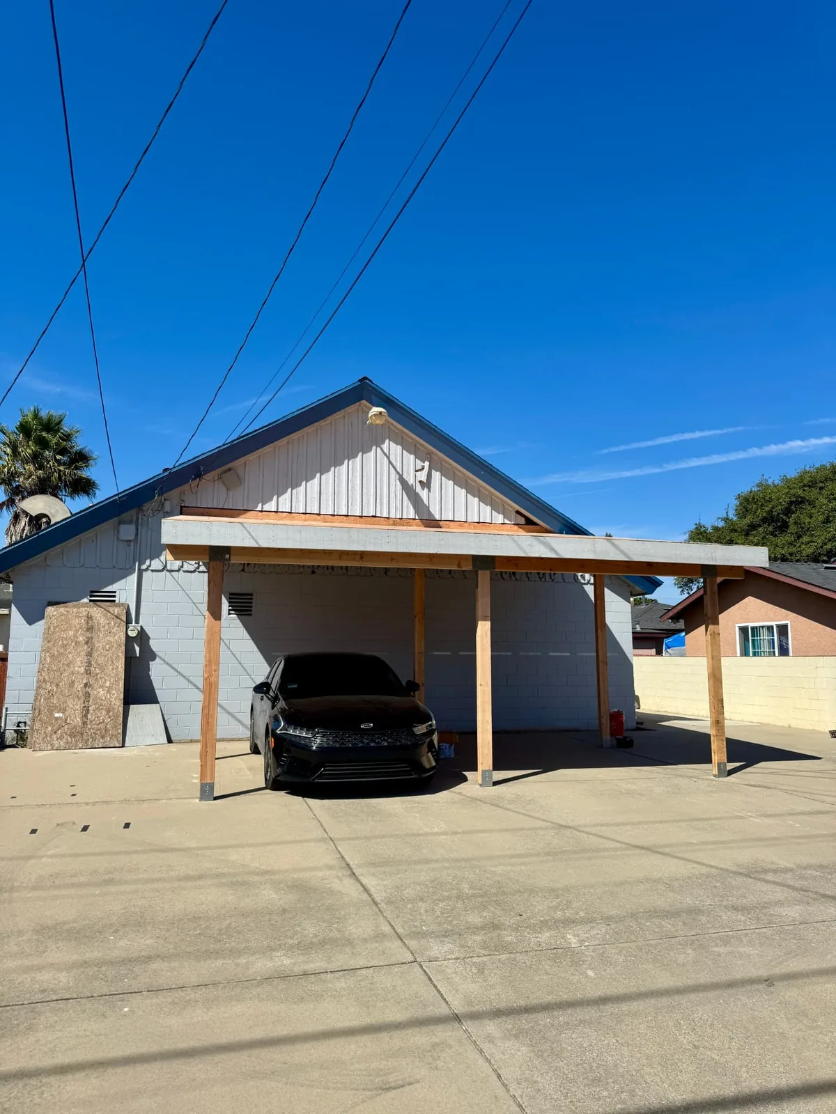 Finished attached carport with posts and beam roof beside a church building in Santa Maria by Mau & Co